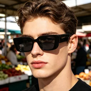 Close-up of stylish men's rimless black rectangular sunglasses in a vibrant outdoor market