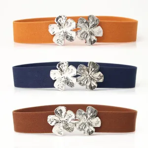 Detailed close-up of elastic waist belts in three colors with silver floral metal buckles
