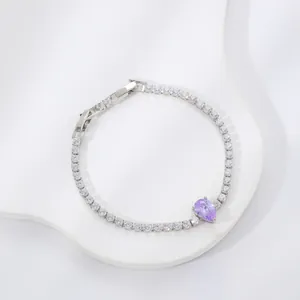 Tennis bracelet with round clear stones and a purple pear-cut centerpiece on white plate