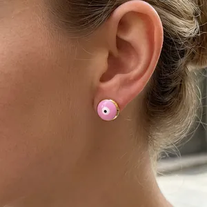 Pink evil eye stud earrings with 18K gold plating and enamel details on model