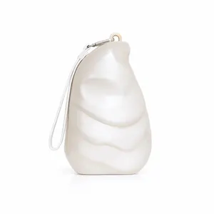 Detail shot of pearlescent white acrylic evening bag with smooth wavy shell texture