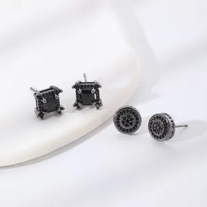 Detail of square and round black zircon stud earrings on a white ceramic display tray