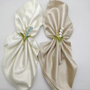 Blue and white lily of the valley alloy napkin rings with enamel finish on white plates