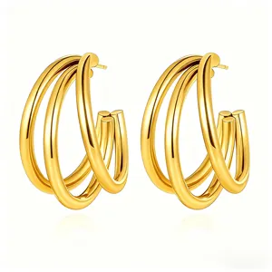 Detailed close-up of triple-layered golden C-shaped hoop earrings with polished finish