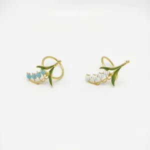 Detail of blue and white lily of the valley napkin rings with golden alloy leaves