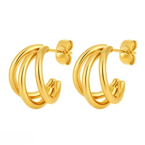Detail of triple-layered C-shaped gold hoop earrings with polished metallic finish