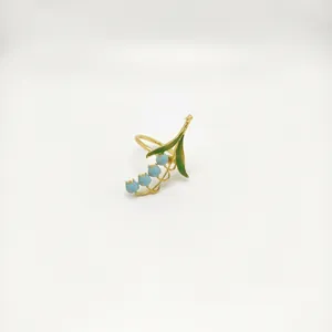 Close-up of blue bellflower napkin ring with gold alloy finish and green leaf details