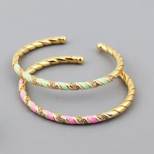 Detail of gold twisted bangles with pink and mint enamel and white crystal accents