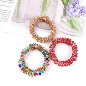 Detailansicht von drei elastischen Kristallperlen-Haargummis in Gold, Rot und Bunt