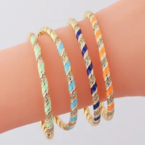 Detail of gold plated twisted enamel bangle with colorful stripes and crystal accents