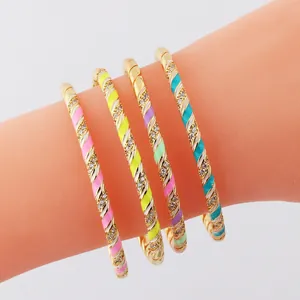 Close-up of gold-plated twisted bangles with colorful enamel and sparkling rhinestones