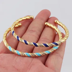 Detail of twisted gold-plated bangles with colorful enamel inlay and sparkling crystals