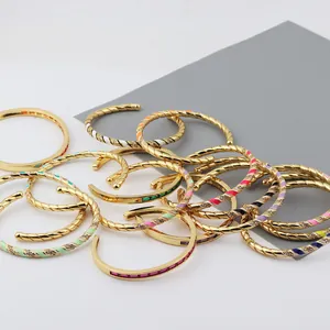 Detail of gold-plated twisted bangles featuring colorful enamel stripes and zircon accents