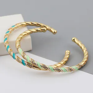 Detail of gold twisted cuff bangle with teal enamel finish and micro-set cubic zirconia