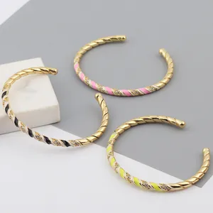 Detailed view of twisted gold-plated bangles with colorful enamel and zircon stones