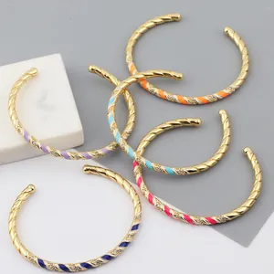 Detail of gold-plated twisted bangles with colorful enamel and micro-set zircon accents