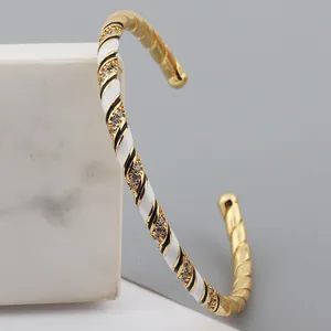 Macro detail of gold-plated twisted bangle with black and white enamel and zircons