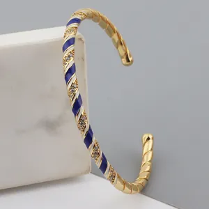 Detailed macro view of gold-plated twisted bangle with blue enamel and zircon stones
