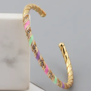 Detail of gold-plated twisted bangle with colorful enamel sections and inlaid crystals