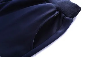 Detail of dark blue knit trousers featuring side pocket and ribbed elastic waistband