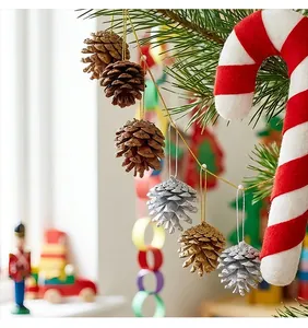Detail of pine cones with gold and silver glitter and a red candy cane on a tree branch
