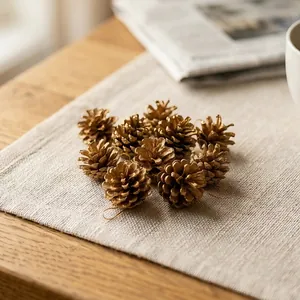 Set of golden pine cone ornaments for Christmas tree decoration on rustic linen