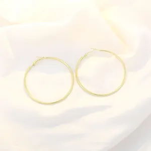 Detail shot of large gold hoop earrings with mirror polish finish on silk background