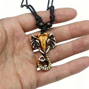 Resin elephant head pendant necklace with tribal carvings on a black woven cord