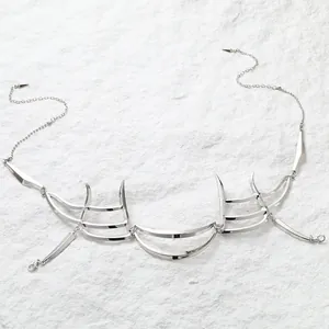 Detalle de máscara facial punk plateada con bordes mecánicos afilados y cadenas