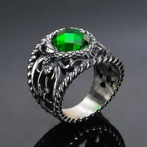 Close-up of gothic vintage men's ring with emerald green stone and dragon relief