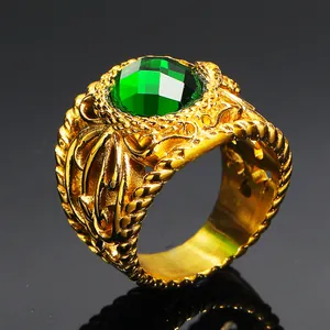 Macro detail of vintage gold ring with large emerald green gem and embossed texture