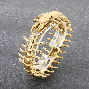 Primo piano di un bracciale a forma di centopiedi in acciaio dorato con dettagli punk.