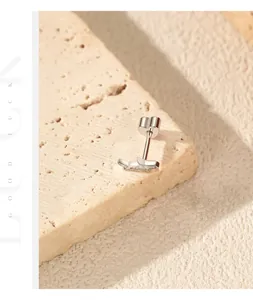 Close-up of S925 sterling silver helix stud earring with moissanite on textured stone