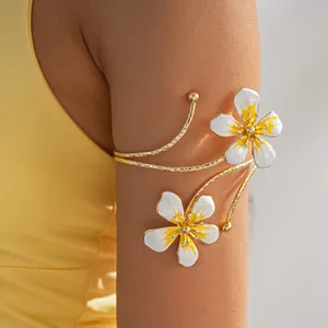 Detailed macro shot of a vintage gold arm cuff featuring white and yellow enamel flowers