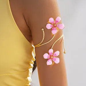 Detailed view of vintage gold metal armlet with pink enamel flowers on upper arm.