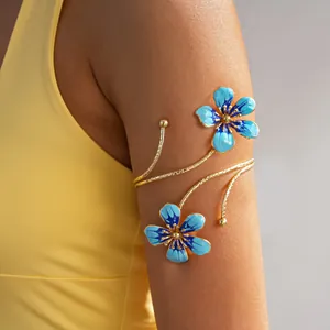 Close-up detail of a vintage gold metal arm cuff with vibrant blue enamel flower designs