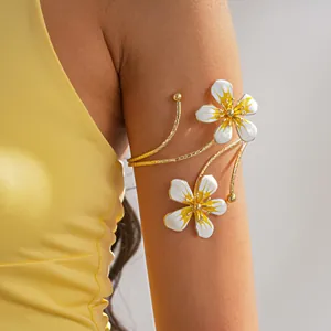 Detail of vintage gold arm cuff with white and yellow enamel flowers on a female model's arm.