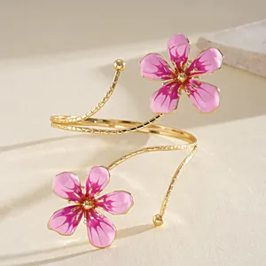 Detailed close-up of a vintage pink enamel flower arm cuff in a polished gold finish.