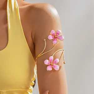 Detail of a vintage gold metal arm cuff with pink oil-drop flowers on a model.