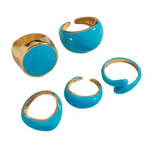 Close-up view of five blue enamel and gold-tone open rings with smooth finishes