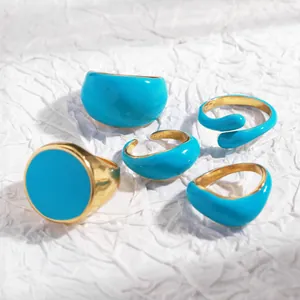 Detailed macro shot of five blue enamel gold stackable rings on a textured white background