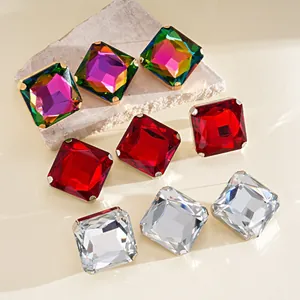 Detalle de pendientes de cristal cuadrados en rojo, blanco y colores irisados