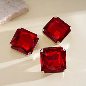 Primer plano macro de pendientes de piedras rojas cuadradas con engaste de garras.