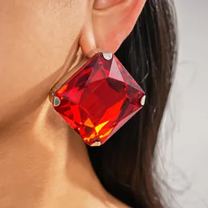 Primer plano de un pendiente cuadrado de cristal rojo de gran tamaño en la oreja