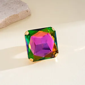 Detalle macro de un pendiente de cristal cuadrado multicolor con engaste dorado