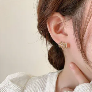 Dettaglio di orecchini a lobo in zircone a più strati placcati in oro 14K all'orecchio