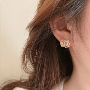 Primo piano di eleganti orecchini a lobo a C multistrato placcati in oro 14K con zirconi