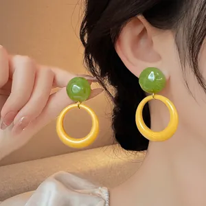 Macro detail view of Mori style green and yellow resin round hoop earrings on model