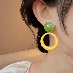 Close-up of vibrant green and yellow resin round earrings worn by a model in forest style