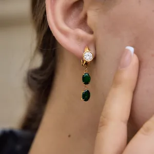 A detailed view of 18k gold plated earrings with sparkling clear and emerald green zircons.